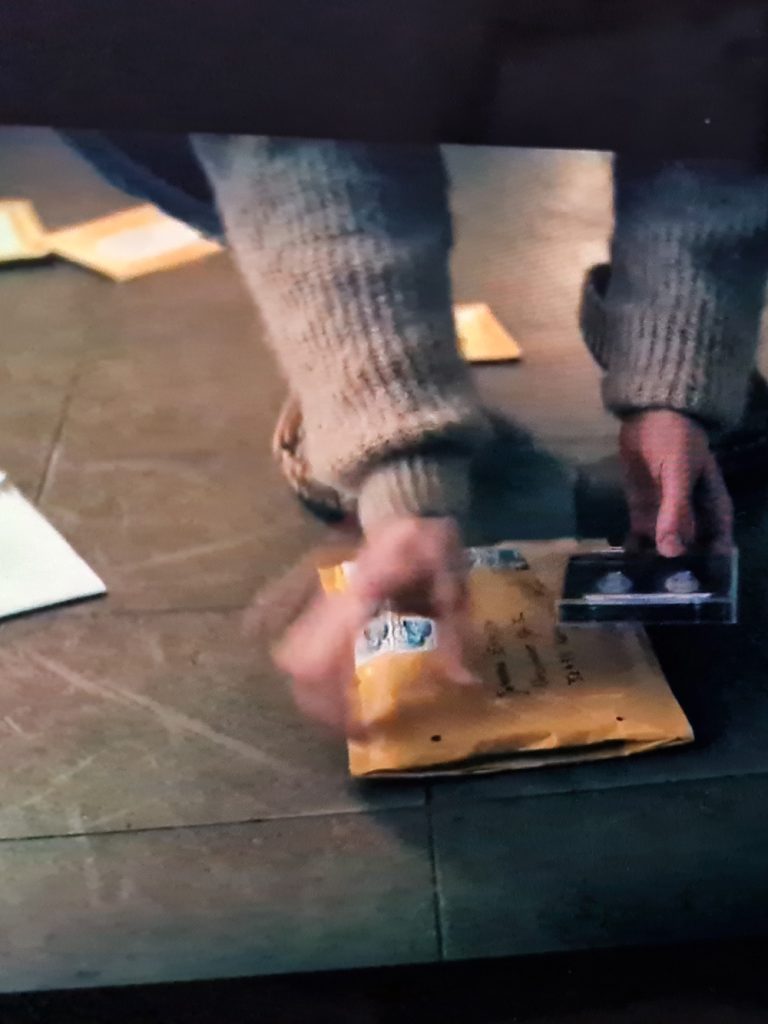 film still from constellation s01e04. two hands holding a cassette that was sent by post.